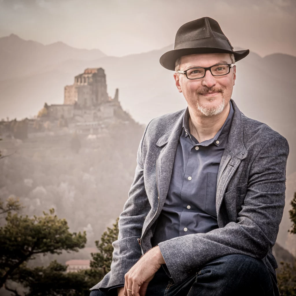 Beppe Roncari sul Sentiero dei Principi davanti alla Sacra di San Michele. Foto: Guido Suardi, 2023.